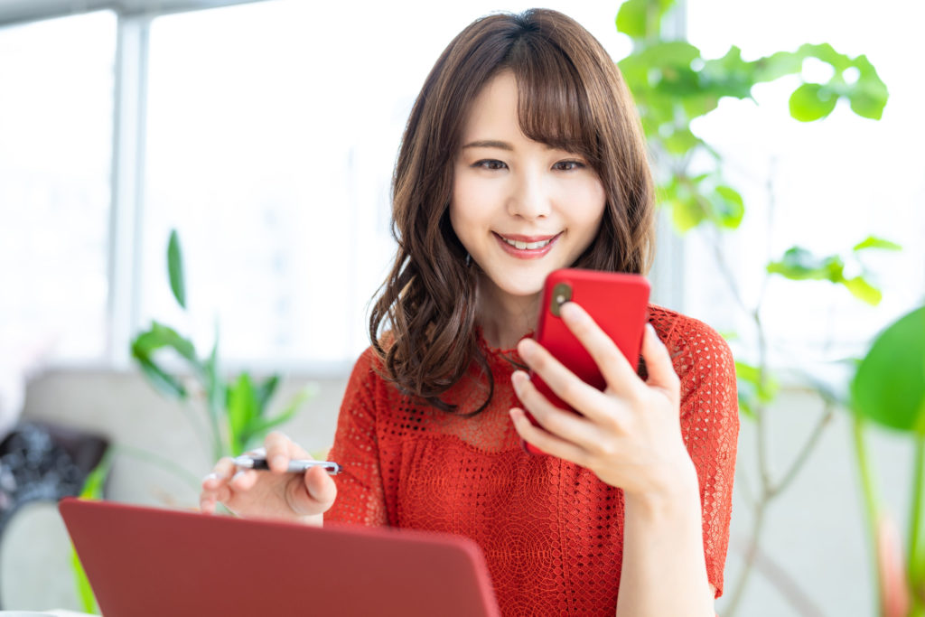 ノートパソコンとスマホ見る女性